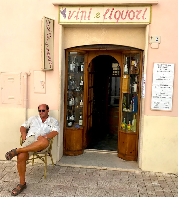 Vinhandlare utanför sin butik i liten by Italien