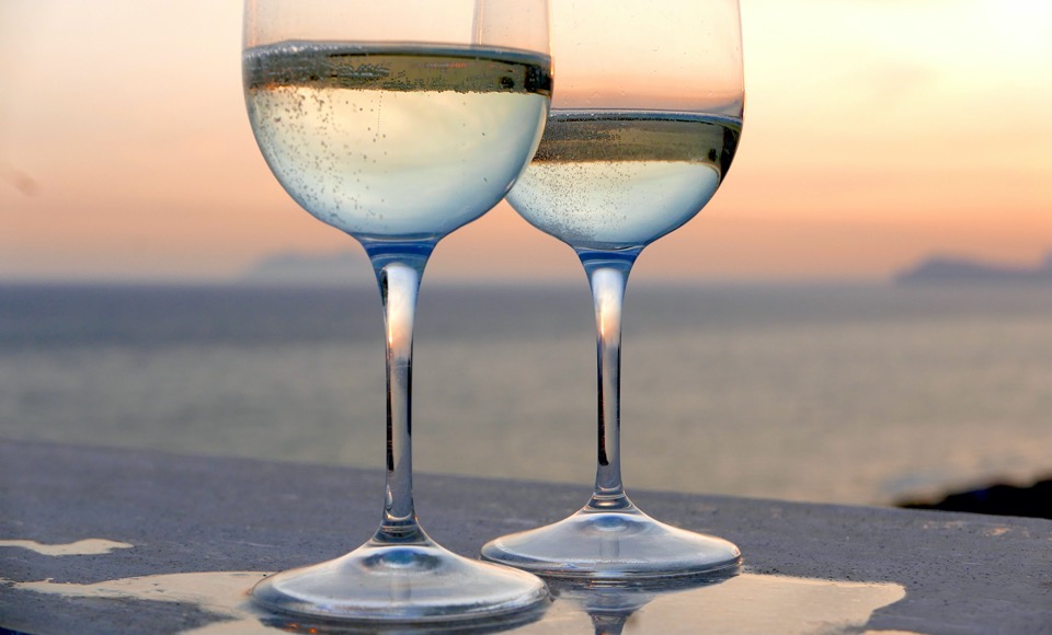 Två glas med mousserande vin, i bakgrunden skymtar man havet.